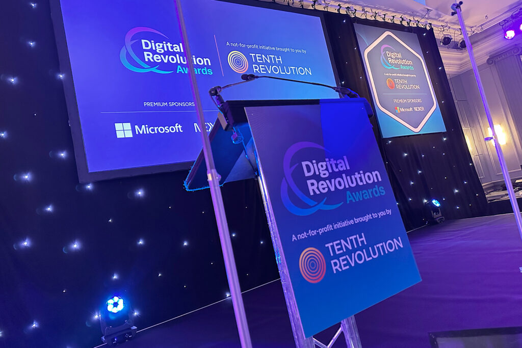 Photo of the Digital Revolution Awards stage showing branded boards and presentation screen